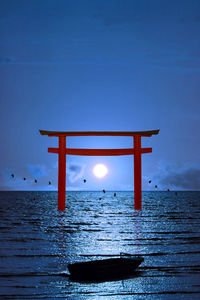Full moon clear night sky over torii and birds flying and fishing boat on sea