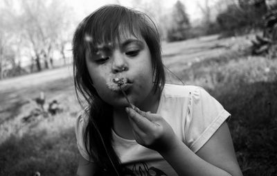 Teenage girl blowing dandelion on land