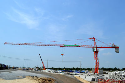 Cranes at construction site against blue sky