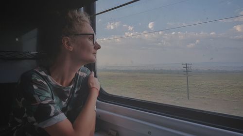 Portrait of young woman looking through window