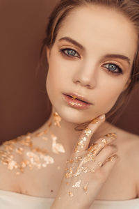 Close-up portrait of beautiful young woman against brown background