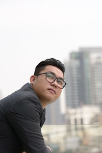 Young man looking away against cityscape