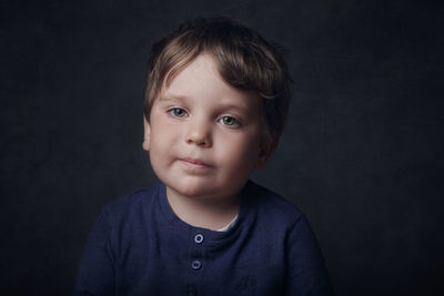 Portrait of cute boy against black background