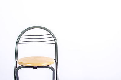 Close-up of empty chair on table against white background