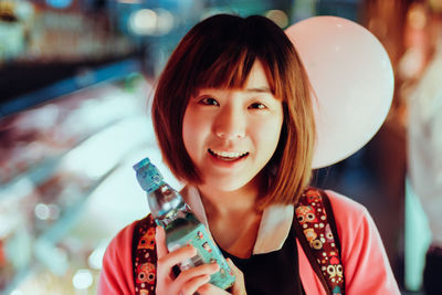 Portrait of smiling young woman holding bottle