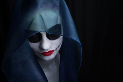 Woman wearing face paint against black background