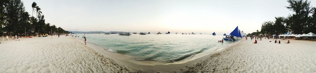 People on beach against clear sky