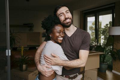 Portrait of happy man embracing girlfriend at new home