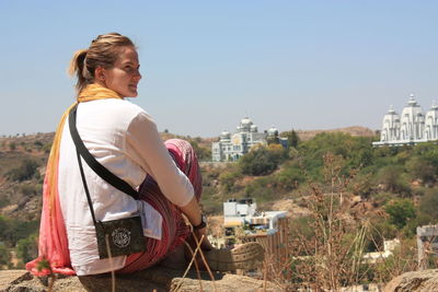 Side view of young woman standing against clear sky