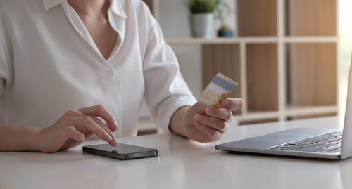 Midsection of woman using smart phone on table