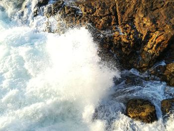 High angle view of waves splashing on rocks