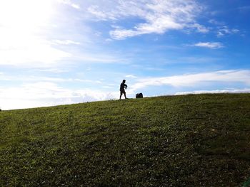 Low angle view of silhouette man walking on grassy hill