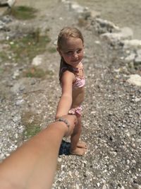 Cute girl holding cropped hand of mother at beach