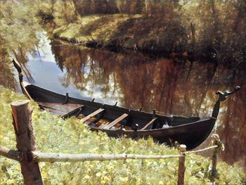 Boat moored by trees on water