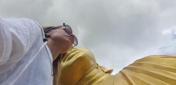 Low angle portrait woman by buddha statue