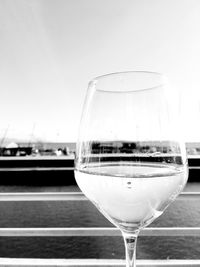 Close-up of wineglass by sea against sky