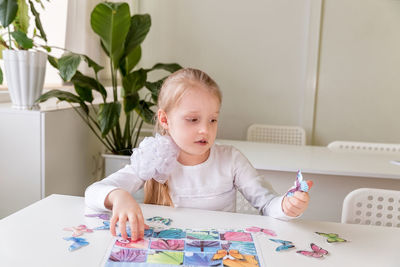 A girl student sits at a desk in the classroom and collects figures / puzzles / small toys 