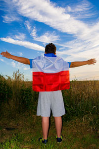 Rear view of woman standing on field against sky