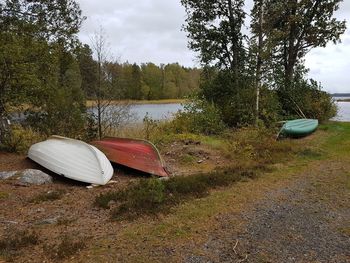 Boat moored on shore by lake against sky