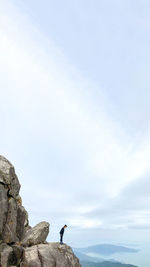 Man standing on rock against sky