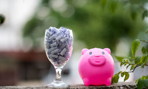 Close-up of piggy bank and wineglass on table