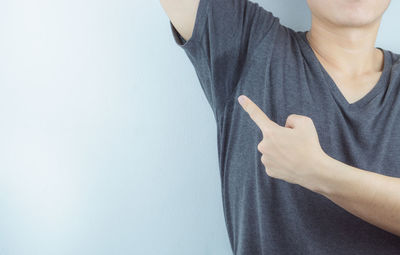 Midsection of man holding hands against wall