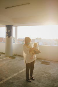 Full length of young mother and his daughter standing in parking lot 