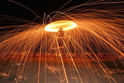 Man spinning wire wool against sky at night