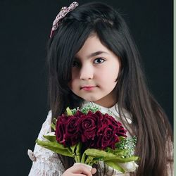 Portrait of young woman with flowers against black background