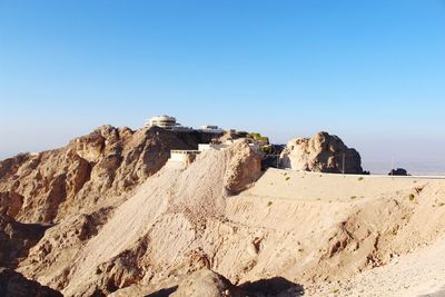 Low angle view of rocks against clear blue sky