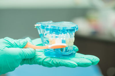 Cropped hands of dentist holding toothbrush and dentures