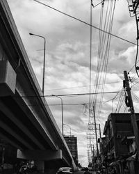 Low angle view of electricity pylon against cloudy sky