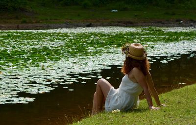 Woman sitting on grass by lake