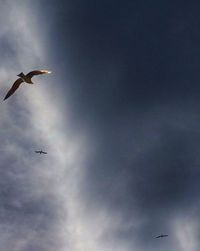 Low angle view of airplane flying against cloudy sky