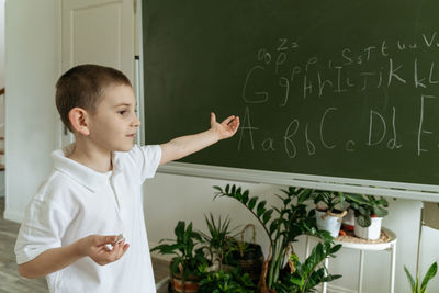 Portrait of boy with text on blackboard