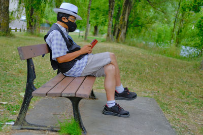 Full length of man sitting on bench in park