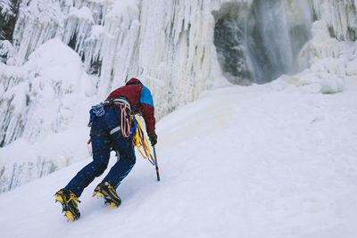 Female ice climber ascending snowy hill