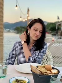 A girl in seaside restaurant. sunset over mountains on a background