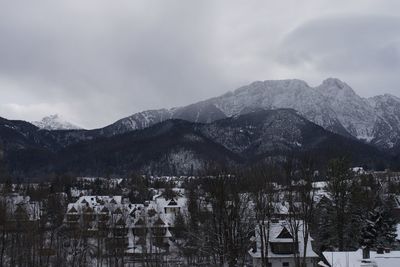 Aerial view of townscape by mountains against sky