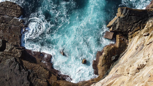 High angle view of waves splashing on rocks