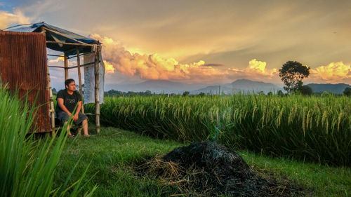 People in farm against sky during sunset