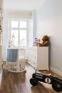 Crib and toy car on hardwood floor at home