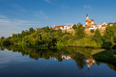 Scenic view of lake by buildings against sky