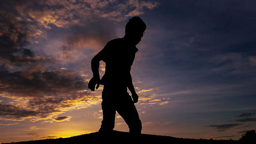 Silhouette man standing against sky during sunset