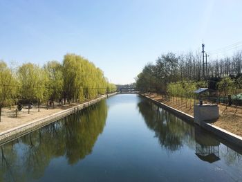 Canal amidst trees against sky