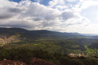 Viewof a mountain range and a green valley in the morning at sunrise, against a dramatic background 