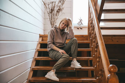 Full length of young woman sitting on staircase