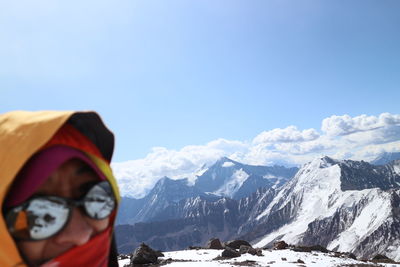 Close-up of man against snowcapped mountains and sky