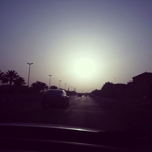 transportation, car, land vehicle, mode of transport, road, clear sky, on the move, street, copy space, road marking, travel, sunset, windshield, the way forward, sky, tree, sun, silhouette, traffic, sunlight