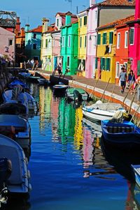 Boats moored in canal amidst buildings in city